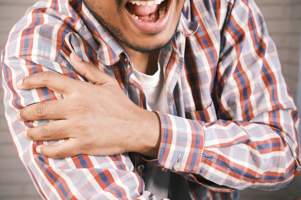 close up photo of an aching man holding his shoulder